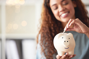 A woman places coins into a piggy bank.