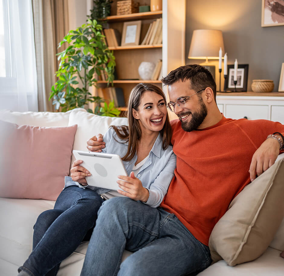 happy-couple-on-sofa-using-tab