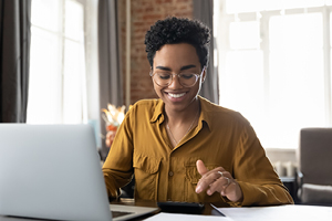 A smiling woman focused on her laptop.