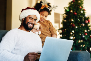 A father and daughter sit together with a laptop.