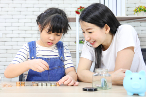 An mother and daughter joyfully placing coins into a piggy bank.