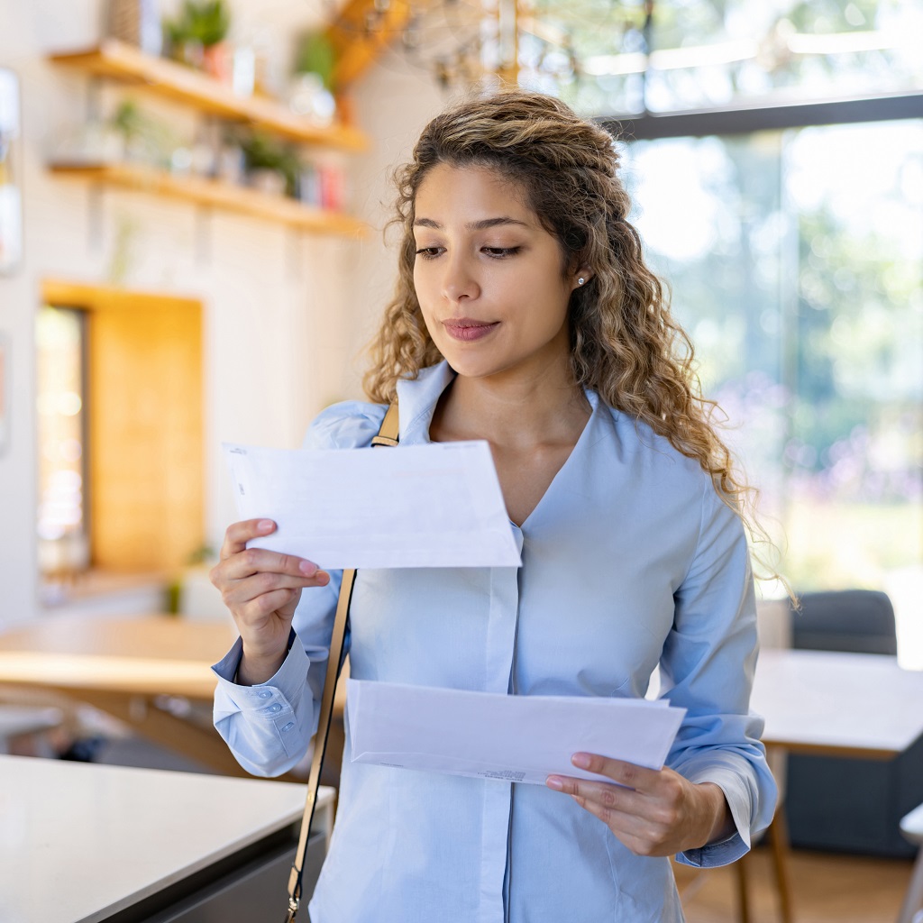 Woman arriving home and reading a letter in the mail