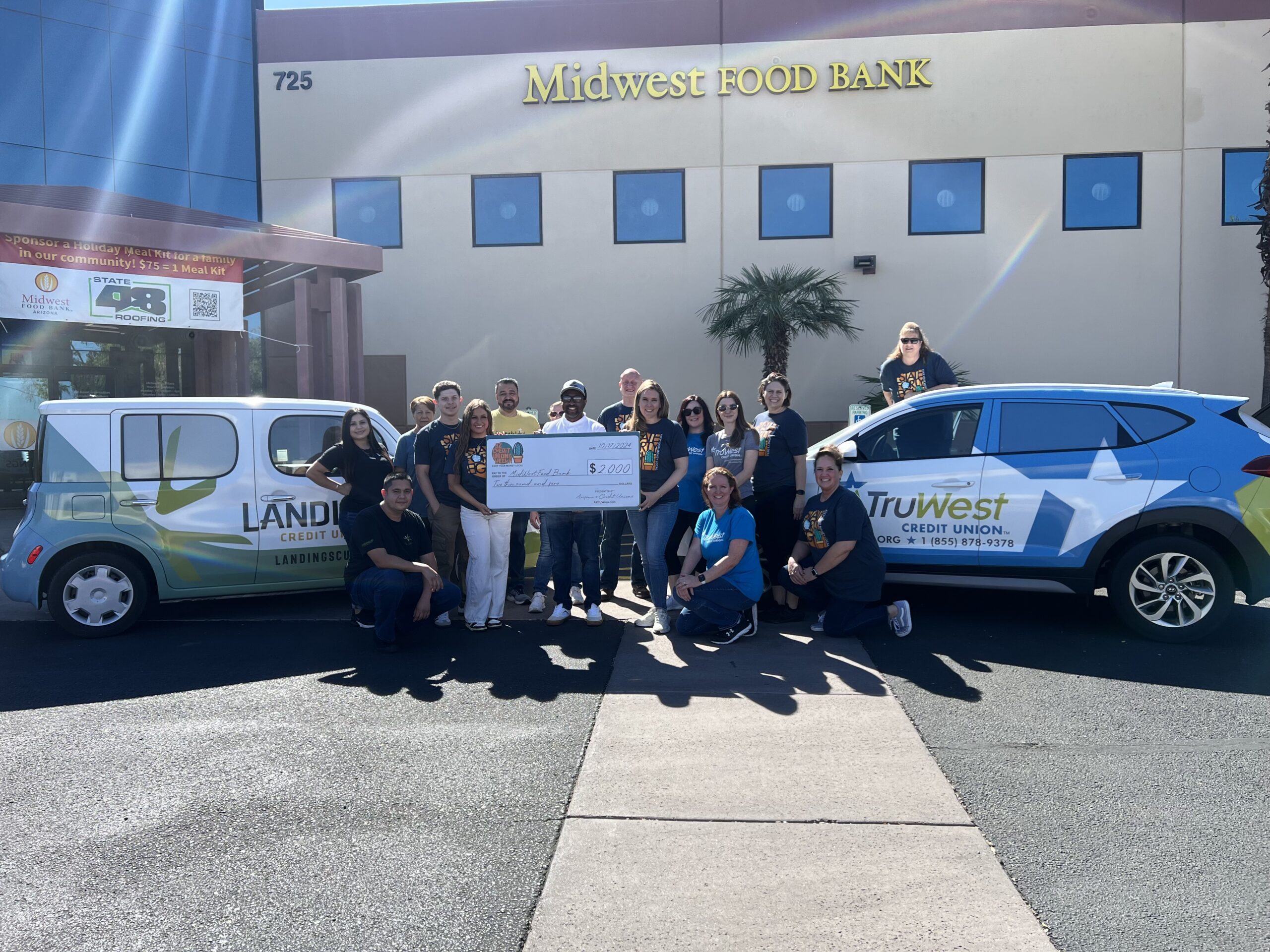 truwest team poses outside a food bank in front of a truwest-branded van during a check presentation