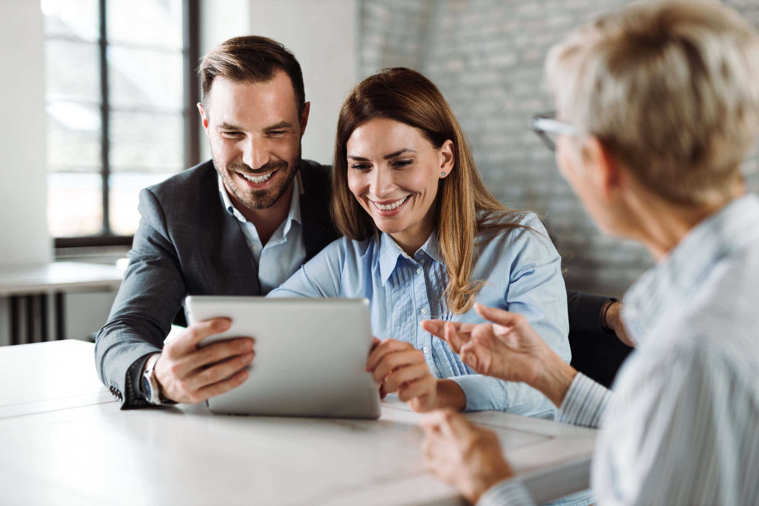 Happy couple using digital tablet on a meeting with insurance agent