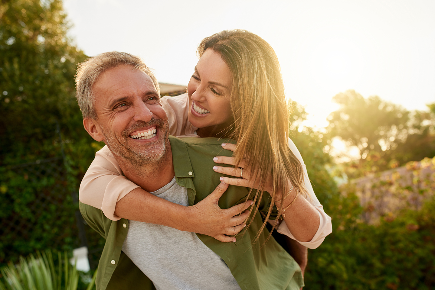 Smiling couple enjoying a piggyback ride outdoors in nature